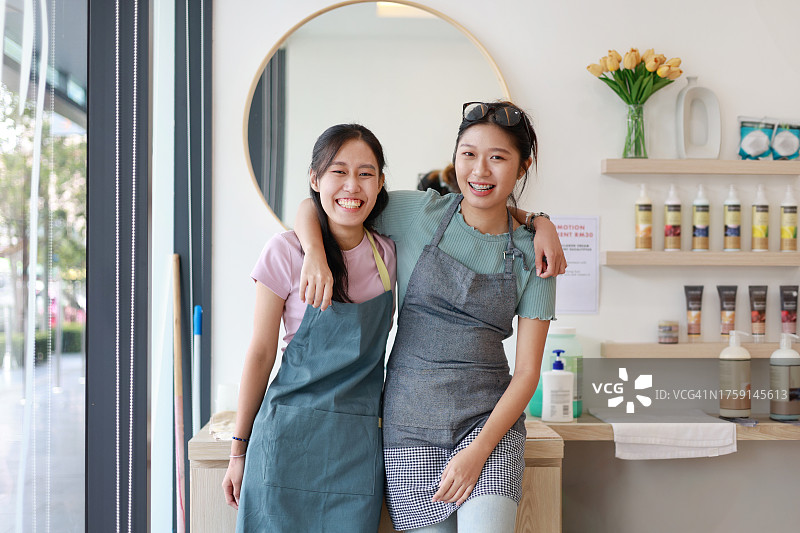 快乐的亚洲女性小企业主在她们的美甲店里一起工作，对着镜头微笑。图片素材