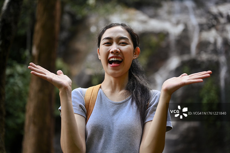 快乐的年轻女子背包客享受大自然与瀑布的背景图片素材