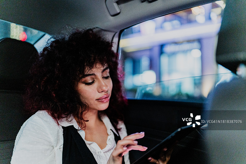年轻的女商人在出租车里使用电子平板电脑图片素材