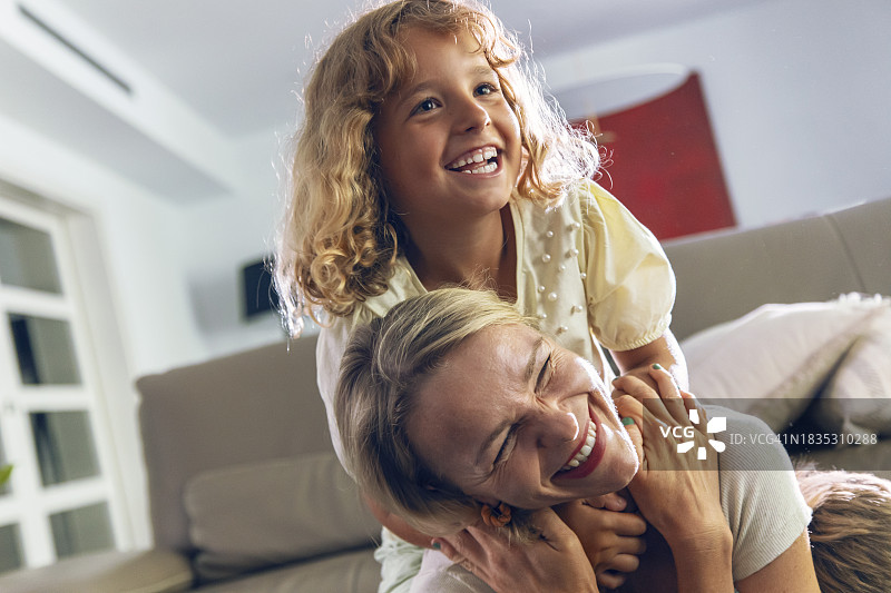 快乐的女孩在客厅拥抱母亲图片素材