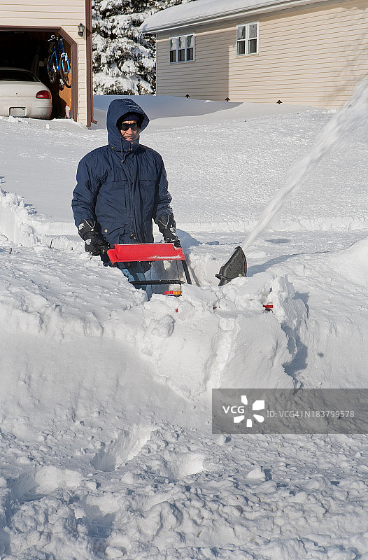 一名男子推着除雪机追赶暴风雪图片素材