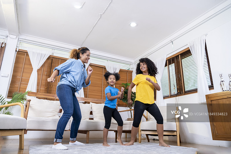 一位母亲和她的两个女儿在客厅里欢快地跳舞图片素材