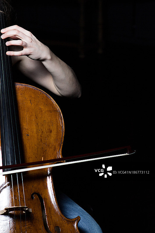 在黑色背景下弹奏大提琴的女人的手的位置图片素材