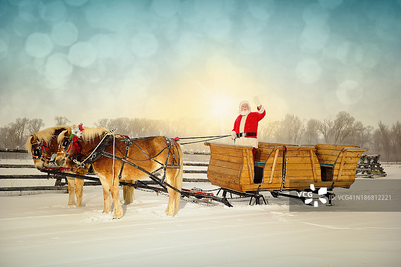 友好的圣诞老人向观众挥手与雪橇和马队图片素材