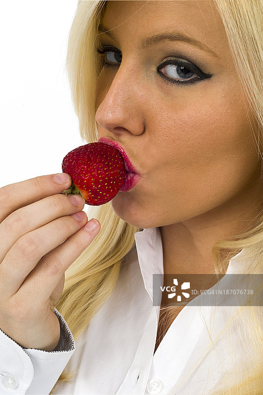 年轻的金发女人吃草莓的特写图片素材