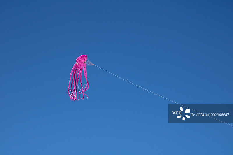 风筝在晴朗的蓝天下飞行的低角度视图图片素材