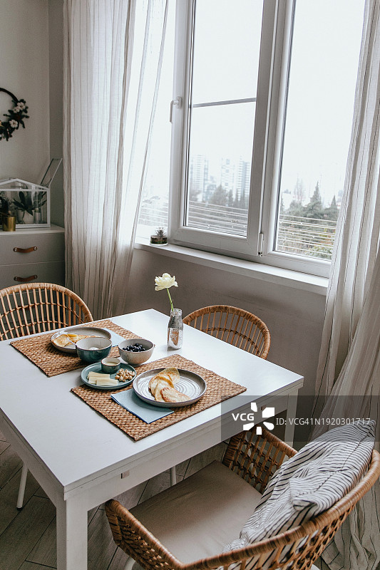 白色斯堪的纳维亚风格的房间，舒适的家，早餐在桌子和扶手椅上图片素材