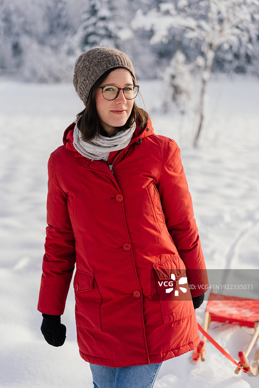 冬天拉着雪橇走在路上的女人看着镜头图片素材