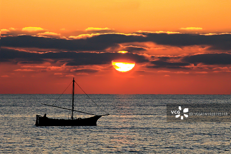 日落时海上帆船的剪影映衬着天空图片素材