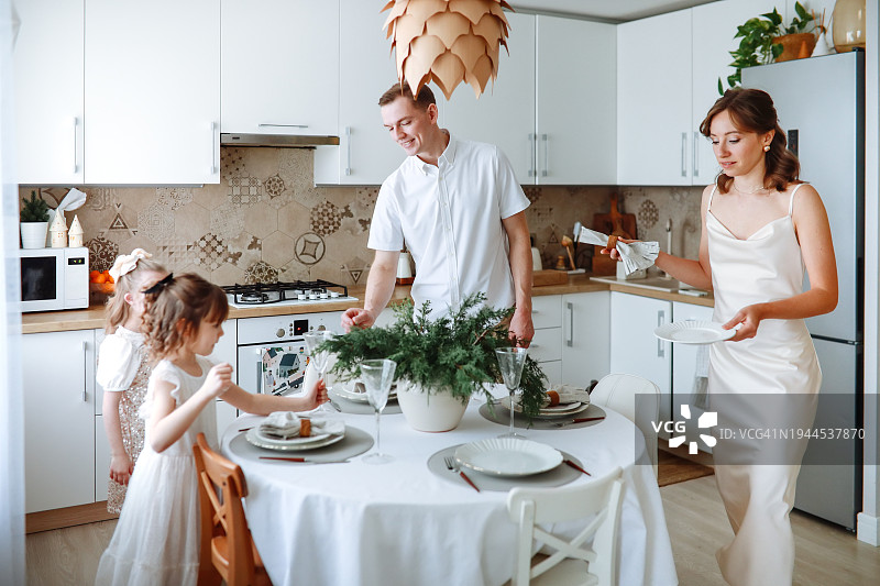 新年优雅:有两个孩子的时尚家庭在家里营造节日的晚餐氛围图片素材