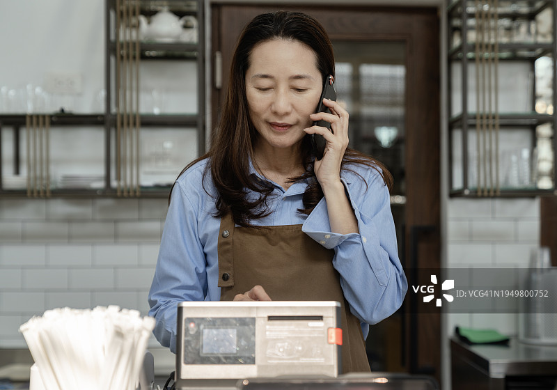 女咖啡师用智能手机接女顾客的订单图片素材