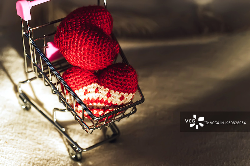 红色编织的心在软背景的购物车里。情人节的概念。图片素材