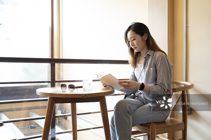年轻的亚洲女性正在休息，在咖啡馆里享受着一杯咖啡和读书的安静时光图片素材