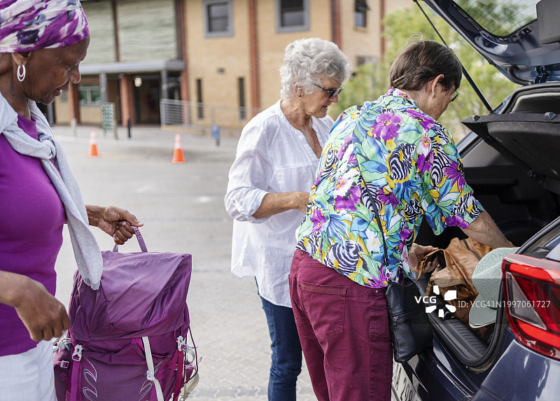 在一次公路旅行中，年长的妇女们一起从车上卸下行李图片素材
