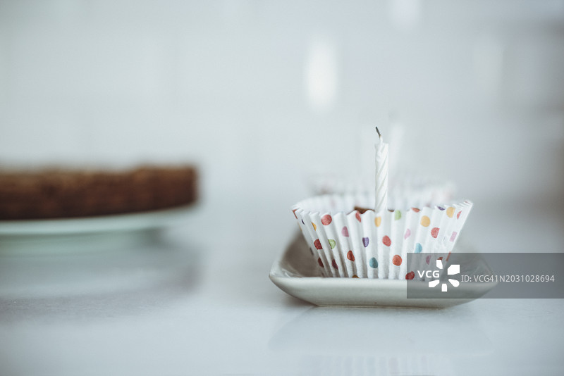 厨房里的盘子里放着两个派对纸杯蛋糕，上面插着生日蜡烛图片素材