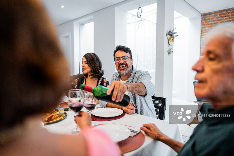 成熟的男人在家里和家人一起享用午餐图片素材