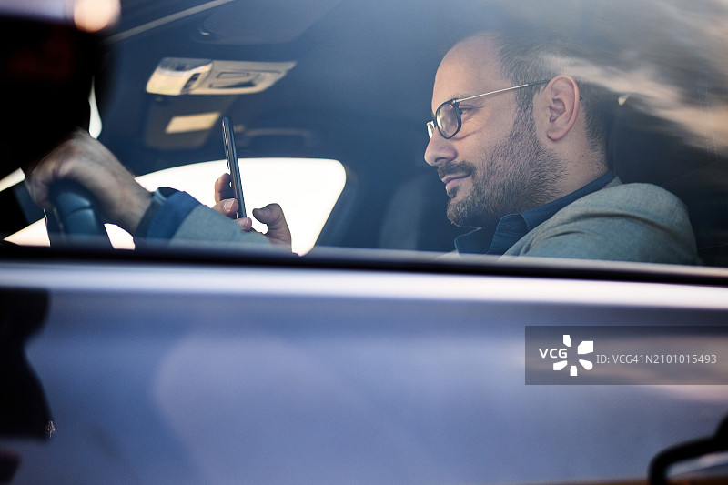 男性企业家一边开车一边打手机。图片素材