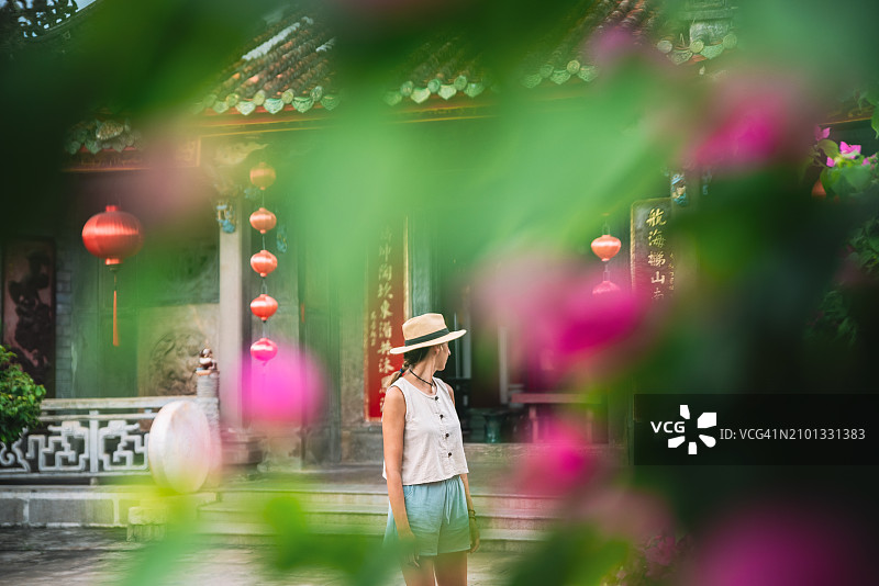 一个女人穿过中国寺庙花园的花丛的艺术照片图片素材