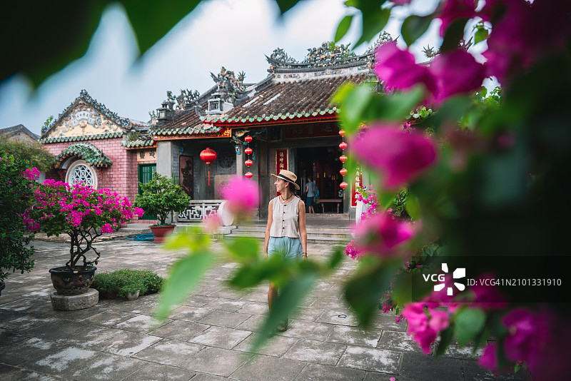 一个女人穿过中国寺庙花园的花丛的艺术照片图片素材
