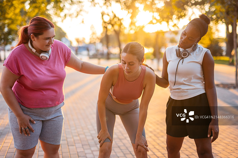 两位女性朋友在公园慢跑后支持她们的朋友图片素材