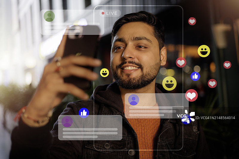 社交媒体:一位男性网红在社交媒体上做视频直播时面带微笑。图片素材