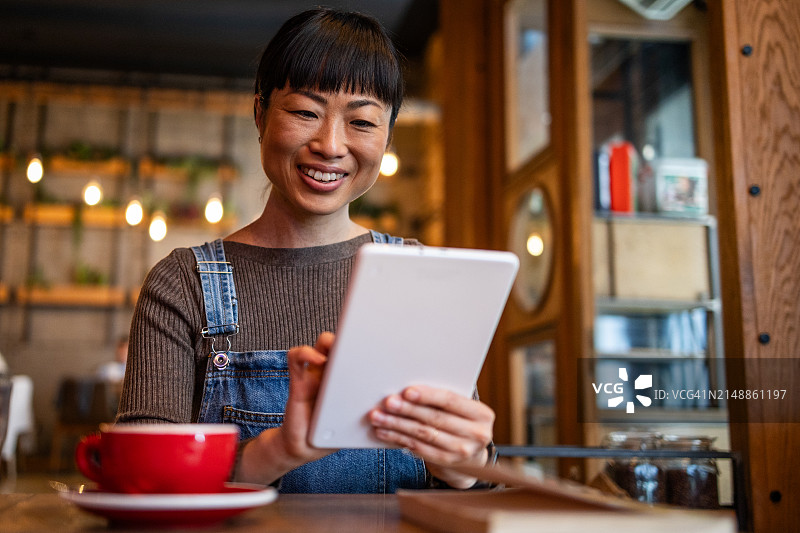 一名日本女子在咖啡馆喝咖啡，用平板电脑与朋友进行视频通话图片素材