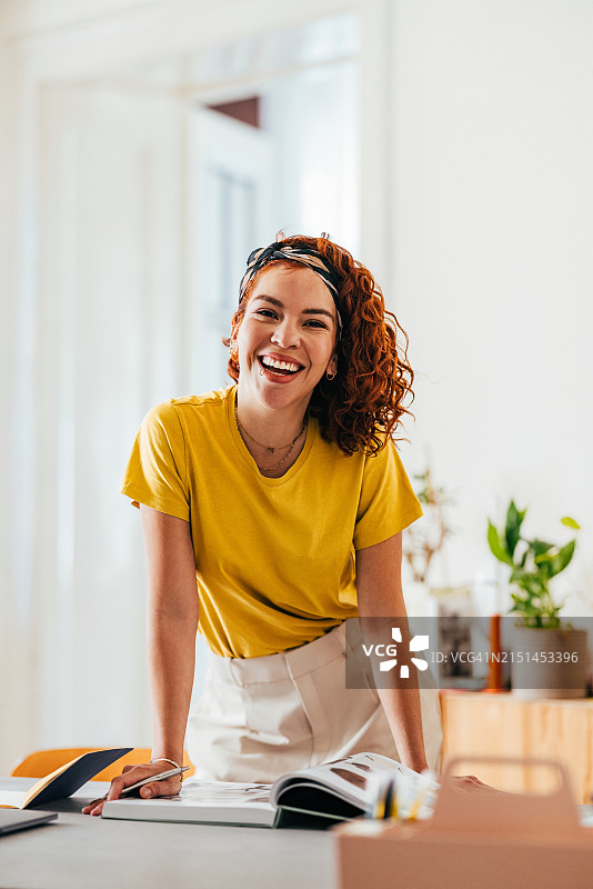 穿着黄色t恤的微笑年轻女子在家快乐地工作图片素材