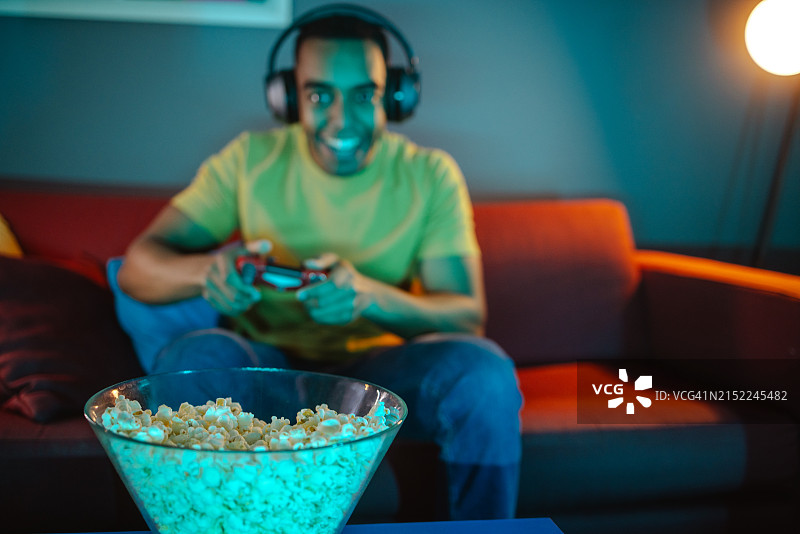一个非裔美国年轻人一边玩电子游戏一边吃爆米花图片素材