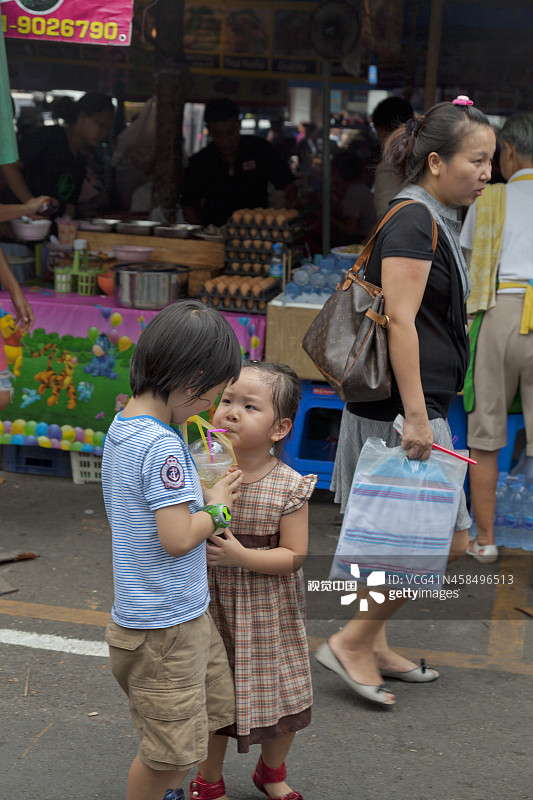 两个泰国孩子在曼谷市场分享软饮料。图片素材