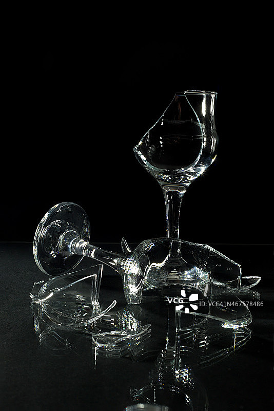 破碎的酒杯与反射在玻璃桌上孤立图片素材
