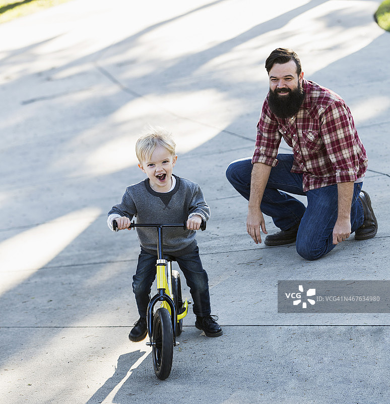 父亲教他的小男孩骑自行车图片素材