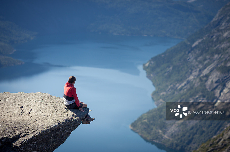 一名男子坐在挪威巨魔之石上图片素材
