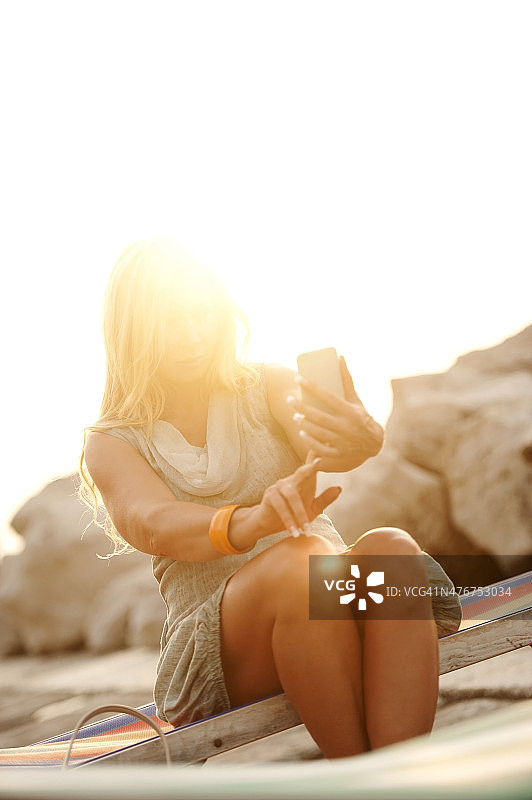 成熟的女人在日落时用手机拍照图片素材