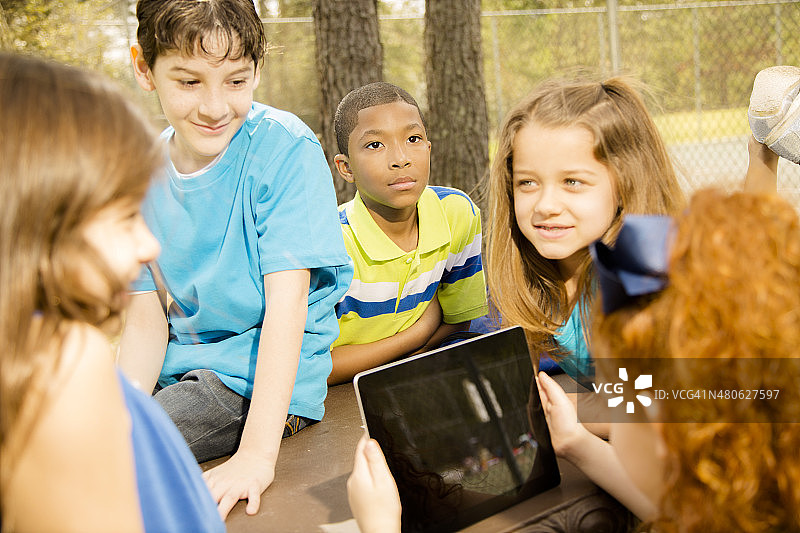 科技:学校的孩子们喜欢在公园的户外平板电脑。图片素材