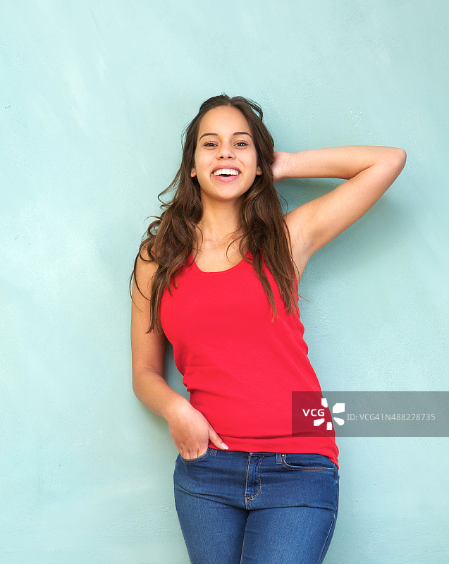 穿着红衬衫的年轻女子微笑着，手挽着头发图片素材