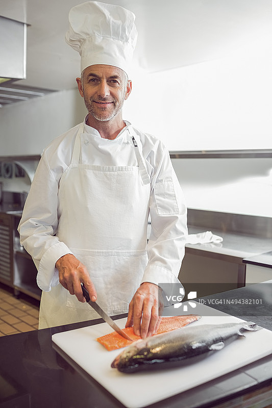 微笑的男厨师在厨房切鱼图片素材