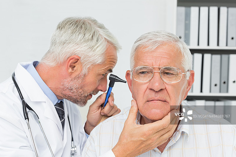 一个男性医生检查老年病人的耳朵的特写图片素材