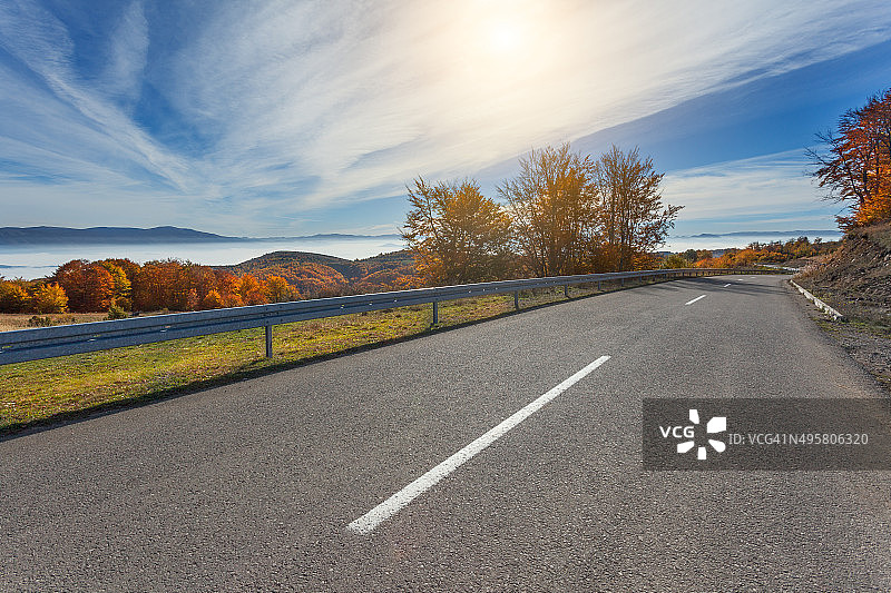 在美丽的秋天的早晨，开车行驶在山路上图片素材