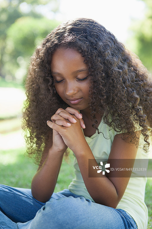 小女孩在公园里祈祷图片素材
