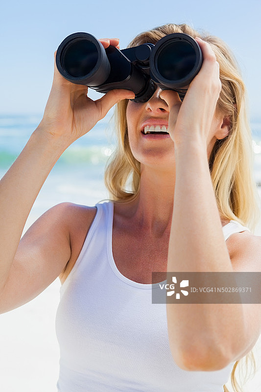 金发女人在海滩上用望远镜看东西图片素材