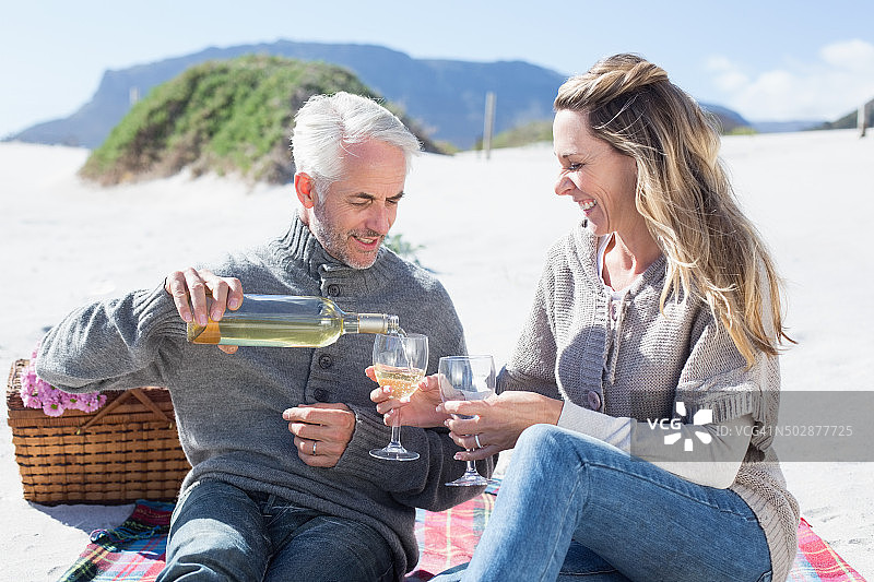 一对夫妇在海滩野餐时享用白葡萄酒图片素材