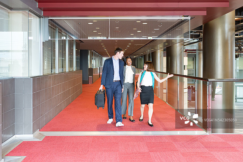 国际商务人士一起走在办公楼的走廊上图片素材