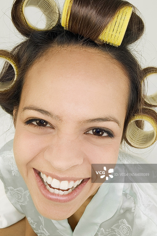 高角度的微笑的年轻女子与卷发在她的头发图片素材