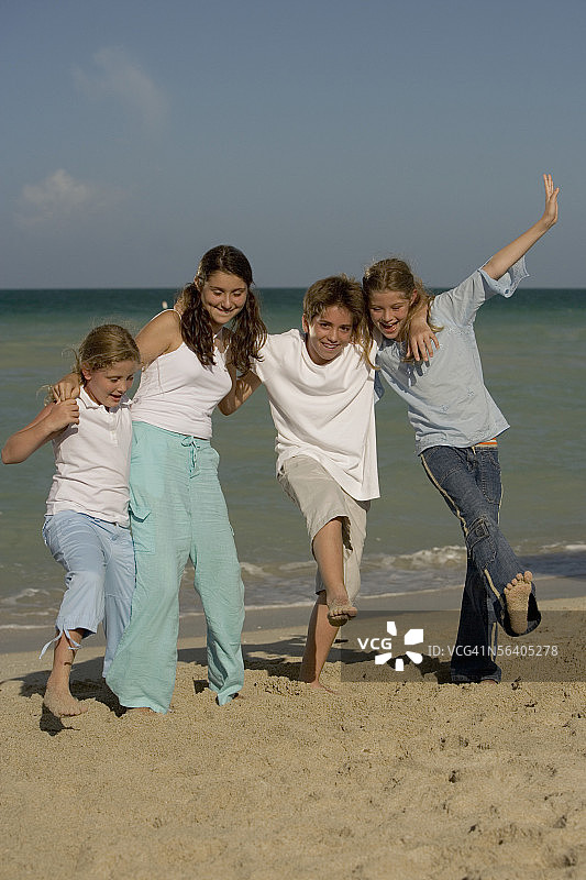 三个女孩和一个男孩在海滩上跳舞图片素材