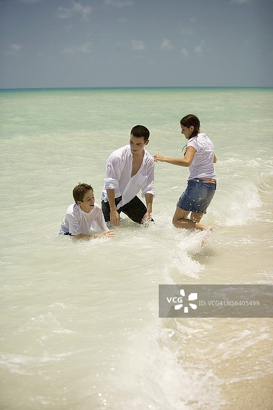 一个年轻人和一个十几岁的女孩和一个男孩在沙滩上玩耍图片素材