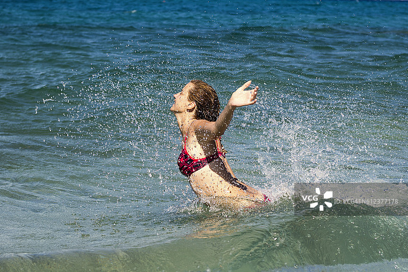 快乐的年轻女子在水里嬉戏跳跃图片素材