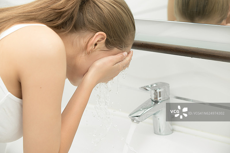年轻女性洗她的脸自来水附近的水槽图片素材