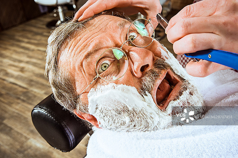 老人在理发店里拜访发型师。图片素材