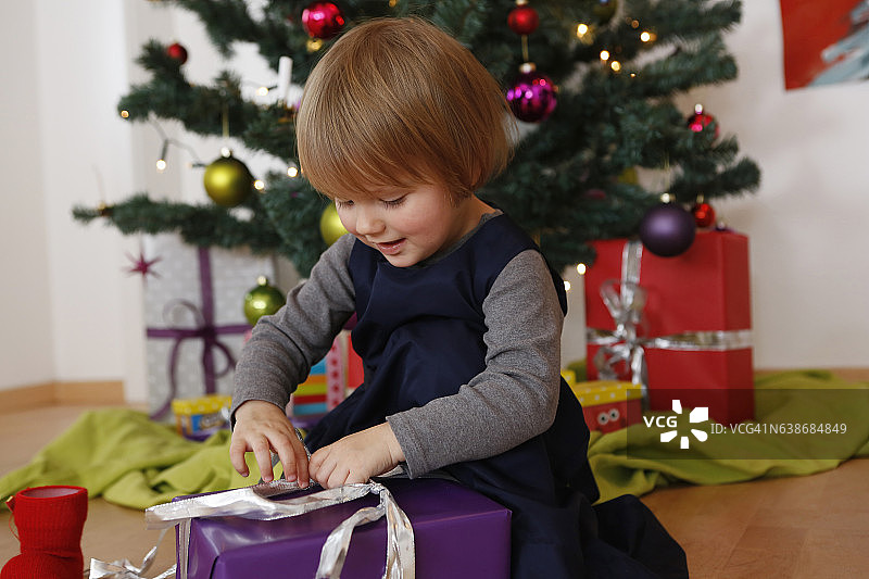女孩在圣诞树前看着打开礼物图片素材