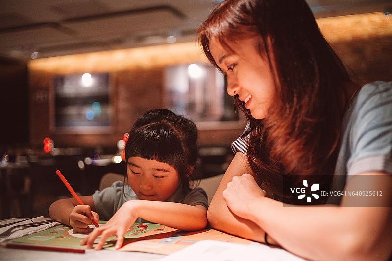 漂亮的年轻妈妈和可爱的小女儿在餐馆里画画图片素材